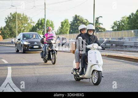 Coppia senior in moto nel traffico cittadino. Motociclisti che guidano moto e auto su strada. Pendolari. Milano, Italia - 26 maggio 2 Foto Stock