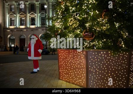 Londra a Natale 2025 - Babbo Natale accoglie i turisti a Waterloo Place, dove si trova un grande albero di Natale di fronte al Sofitel St James Hotel Foto Stock