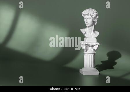 Testa in marmo bianco del giovane, testa della famosa statua di Michelangelo - David di Firenze. Copia gesso dell'antica testa della statua su sfondo verde wi Foto Stock