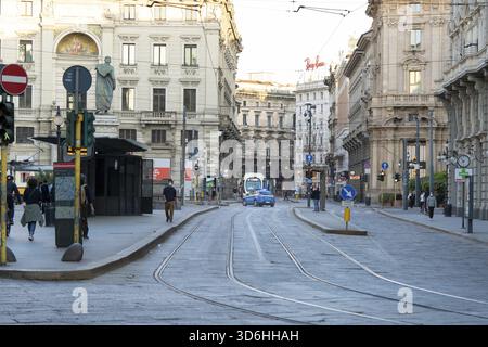 Milano, Italia - 4 maggio 2020: Le persone camminano per le strade della città indossando la maschera. Fermata del tram. La polizia in auto tiene ordine per le strade. L'Italia entra in s. Foto Stock