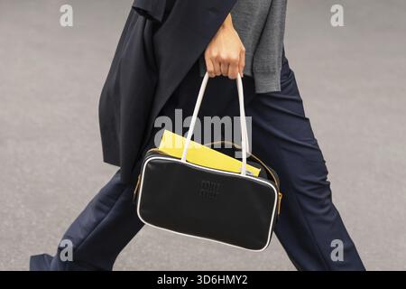 Parigi, Francia - 11 marzo 2025: Borsa Miu Miu in bianco e nero con pantaloni blu navy. Outfit Street style Foto Stock