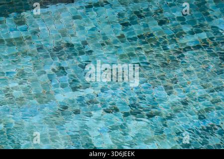Rinfrescante fondo di acqua blu della piscina con pavimento piastrellato a mosaico. la luce calma e scintillante si riflette sulle ondulazioni, creando un sereno astratto Foto Stock