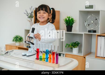 scienziata felice che impara la scienza con un microscopio Foto Stock