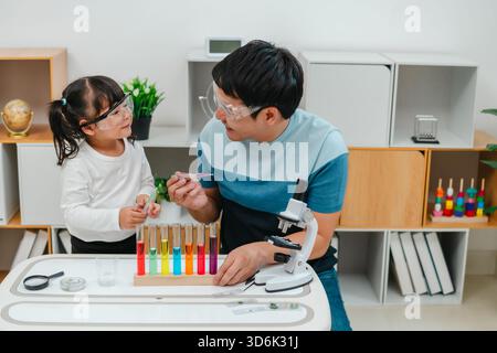 studio scientifico della bambina con l'utilizzo del liquido contagocce per pipette con provetta e becher. imparando la scienza con suo padre Foto Stock
