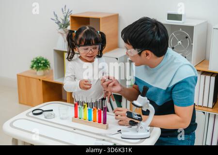 studio scientifico della bambina con l'utilizzo del liquido contagocce per pipette con provetta e becher. imparando la scienza con suo padre Foto Stock