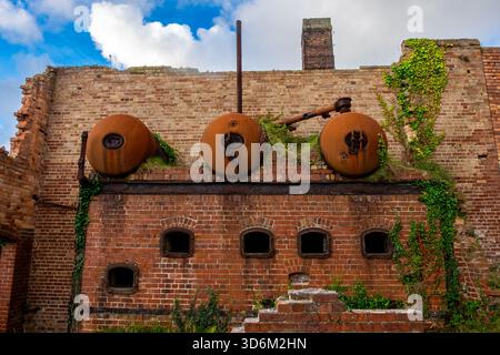 Tre caldaie cilindriche corrose montate su una parete in mattoni presso Porth Wen Brickworks Foto Stock