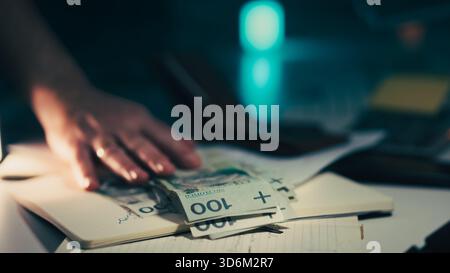 Consegna a mano il pagamento delle banconote Zloty polacche. Primo piano maschio che posiziona banconote spesse da 100 PLN sulla scrivania con i documenti del notebook durante il tran finanziario Foto Stock