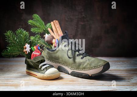 Sneaker piccola e grande piena di dolcetti nel giorno di Nicola o Nikolaus al 6 dicembre, tradizione natalizia in Germania, periodo natalizio, spazio fotocopie, sele Foto Stock