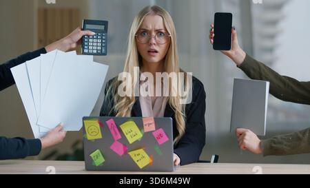 Donna d'affari stressata in ufficio mani femminili che danno telefono notebook carta calcolatrice da lati multitasking frustrata donna d'affari che tiene in mano Foto Stock