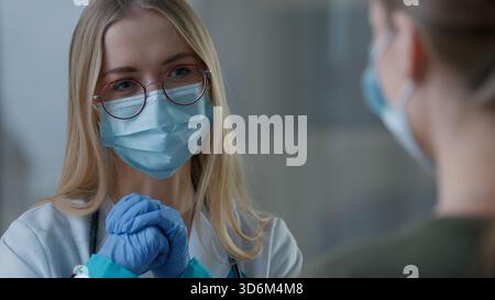 Primo piano donna caucasica dottore parlare conversazione con ragazza paziente due donne in faccia maschera medica in clinica parlare medicina consultazione Foto Stock