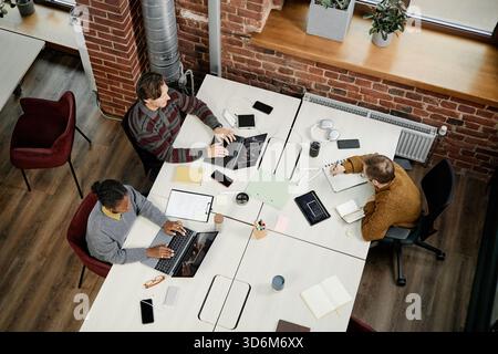 Diversi giovani colleghi adulti che collaborano con notebook in un ufficio moderno Foto Stock