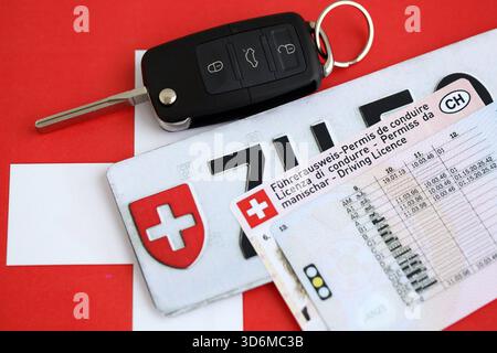 Targa Svizzera e chiave di accensione sulla bandiera svizzera primo piano. Patente di guida e concetto di immatricolazione Foto Stock