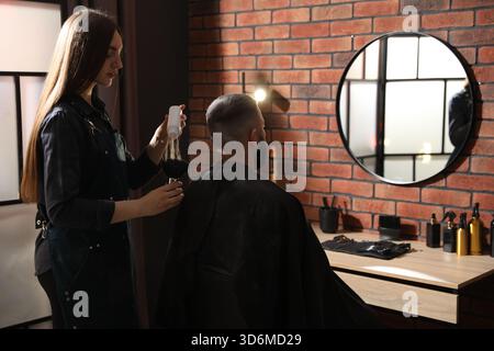 Donna che mette polvere di talco sulla spazzola e il suo cliente al salone Foto Stock