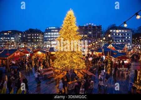 Zurigo, Svizzera, 20 novembre 2025. Albero di Natale alto e decorato e persone che visitano il mercato di Natale di Sechselautenplatz. Ora blu nuvolosa, ma Foto Stock
