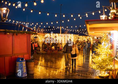 Zurigo, Svizzera, 20 novembre 2025. Persone che visitano negozi pop-up e bancarelle al mercato di Natale di Sechselautenplatz. Ora blu nuvolosa, molti hangi Foto Stock