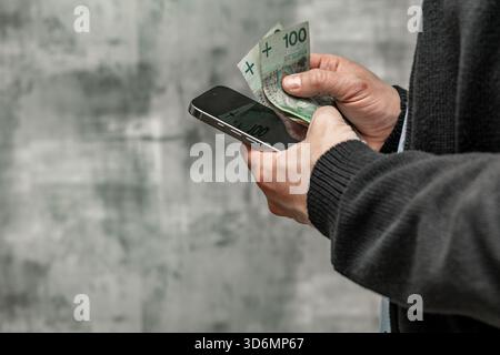 Un uomo con una camicia blu e un maglione tiene i soldi in mano, contando i soldi prima di spenderli. Foto Stock