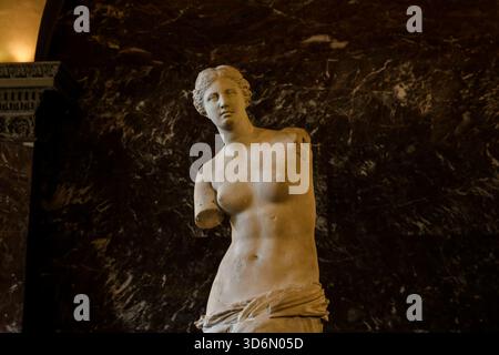 L'antica statua greca Venere di Milo esposta nel Museo del Louvre di Parigi, esposta su uno sfondo di marmo scuro nella galleria di sculture. Foto Stock