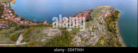 Vista aerea della penisola rocciosa di Lin circondata da acque turchesi, alberi autunnali e case sul lago del villaggio. Foto Stock