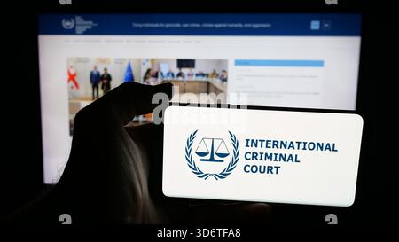 In questa immagine, una persona ha in mano un telefono cellulare con il logo dell'organizzazione Tribunale penale internazionale (ICC) sullo schermo davanti alla pagina Web. Foto Stock