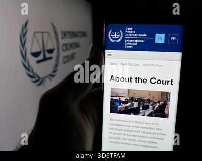 In questa immagine, una persona ha in mano uno smartphone con la pagina Web dell'organizzazione Tribunale penale internazionale (ICC) sullo schermo davanti al logo. Foto Stock