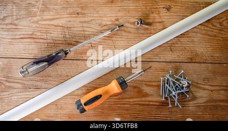 Cacciaviti con viti in metallo diffuso su superfici in legno rustico per progetti di riparazione domestica Foto Stock