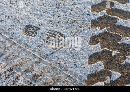 Impronte e tracce lasciate su neve leggera appena caduta. Superficie nevosa morbida e non toccata che mostra tracce umane in un ambiente invernale all'aperto, condizioni meteorologiche Foto Stock