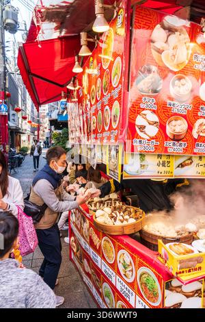Bancarelle di cibo da asporto cinese che vendono panini e gnocchi cotti in contenitori di bambù, serviti al cliente con cibo avvolto. Di giorno Foto Stock