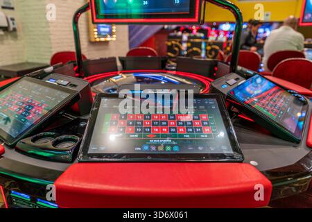 Console roulette elettronica con touchscreen, disposizione delle scommesse, interfaccia di gioco illuminata e tecnologia casinò moderna in un ambiente luminoso. Foto Stock