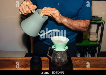 Il barista versa acqua nel gocciolatore di caffè. Foto Stock
