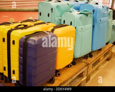 Le valigie da viaggio colorate sono disposte su un pallet di legno in un magazzino o magazzino. L'immagine mostra i bagagli organizzati preparati per il trasporto Foto Stock