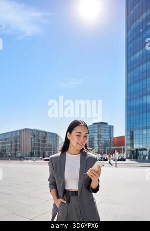 La giovane donna asiatica d'affari indossa il vestito in piedi sulla strada della città usando il telefono. Foto Stock