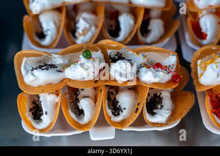 Deliziosa strada Thai dessert, Kanom Buang, Tailandese frittelle croccanti o Thai crêpe con varietà di farciture come bianco e dolce crema pasticcera e golden Foto Stock