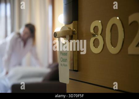 Servizio in camera. Donna che fa il letto in camera d'albergo. Il pulitore della casa prepara tutto per far sì che i clienti si trasferiscano Foto Stock