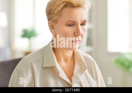 Pensiva piacevole donna di mezza età faccia espressione, sola che sembra triste pensare meditare Foto Stock