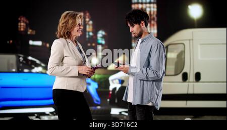 Il conducente si scambia le informazioni assicurative dopo un incidente stradale di notte Foto Stock