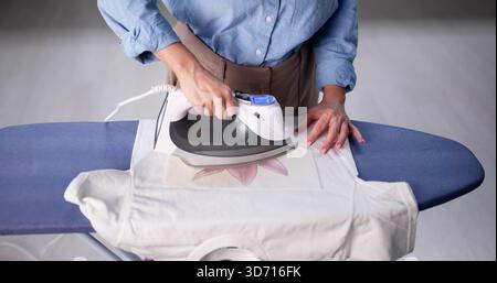 Designer donna che crea disegni di camicie personalizzate utilizzando il trasferimento termico Foto Stock