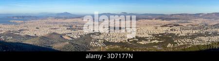 Ampia vista panoramica di Atene dal Monte Imettus, sotto i cieli limpidi del giorno, rivelando fitti isolati della città e colline circostanti Foto Stock