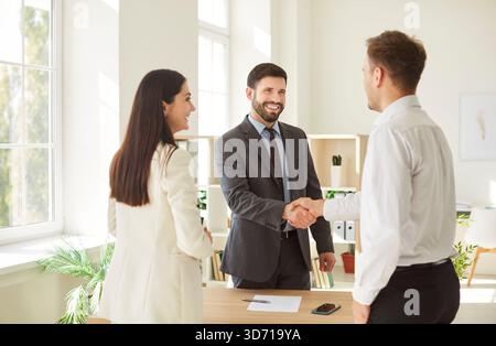 Allegro felice accordo tra uomini e donne in affari che stringe la mano in ufficio, sorride, ridendo Foto Stock