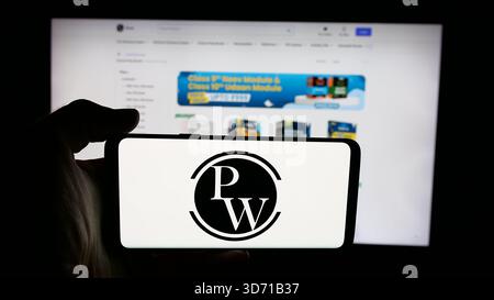 In questa illustrazione fotografica, una persona ha in mano un cellulare con il logo della società indiana Physics Wallah Limited (PW) sullo schermo davanti alla pagina web. (Foto di Timon Schneider / SOPA Images/Sipa USA) *** esclusivamente per notizie editoriali *** Foto Stock