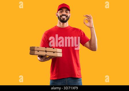 Persona sorridente che tiene le scatole per pizza in un ambiente luminoso, mostrando la gioia della consegna di cibo Foto Stock