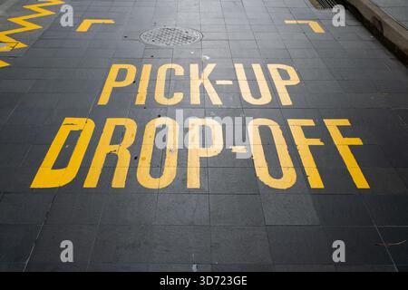 I contrassegni gialli luminosi sul marciapiede indicano le zone di prelievo e rientro a Orchard Road, Singapore, che mostrano le infrastrutture urbane e la gestione del traffico Foto Stock