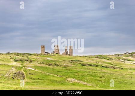 Vecchie rovine su una collina in un paesaggio prato e nuvole scure sul cielo Foto Stock