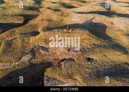 Veduta aerea di una persona seduta su una panchina nel paesaggio erboso carsico unico di Kostivere in Estonia. Foto Stock