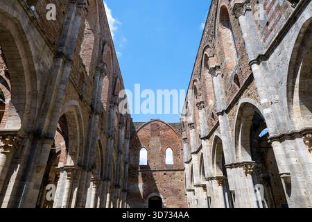 Archi cistercensi gotici dell'Abbazia di San Galgano del XIII secolo a Chiusdino, in Toscana, che mostrano la navata senza tetto sotto un cielo blu. Foto Stock
