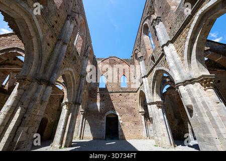 Chiusdino, Italia - 20 luglio 2025: Archi gotici interni dell'abbazia cistercense di San Galgano, senza tetto, sotto un summ chiaro Foto Stock