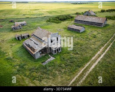 Fattoria desolata e abbandonata con una chiesa e qualche altro edificio. La chiesa è in mezzo al campo Foto Stock