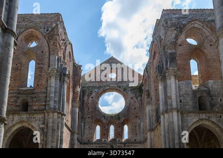 Rovine interne dell'abbazia cistercense di San Galgano del XIII secolo vicino a Chiusdino, con archi gotici in pietra e navata in mattoni senza tetto. Foto Stock