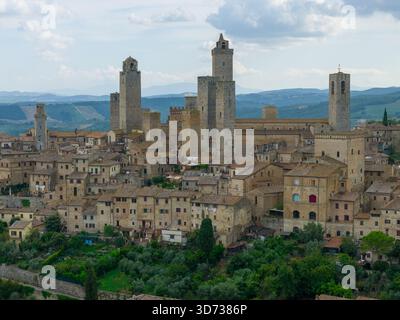 Veduta aerea delle torri medievali in pietra di San Gimignano che si innalzano sopra le mura collinari toscane, ex centro commerciale della via Francigena. Foto Stock