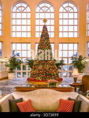 Un albero di Natale splendidamente decorato sorge in una lussuosa lobby, creando un'atmosfera di vacanza calda e invitante Foto Stock