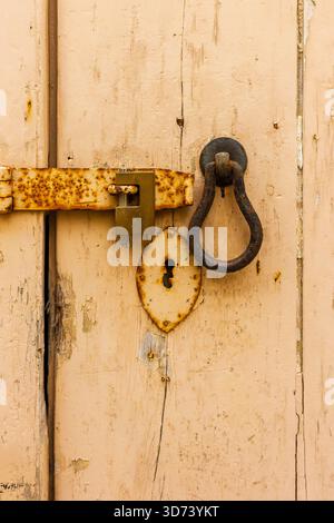 Vecchio lucchetto rustico e serratura su porta in legno beige con guarnizione a chiave Foto Stock